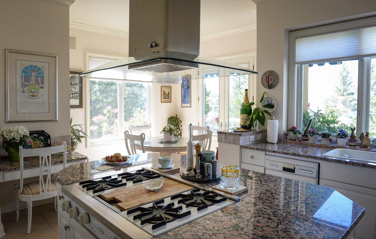 A granite countertop with rose-colored accents covers the kitchen island in front of a breakfast nook with expansive views of the mountains in this European-style estate built in 1993 by Erna Kubin-Clanin, the former owner of Erna's Elderberry House, and her husband René Clanin.