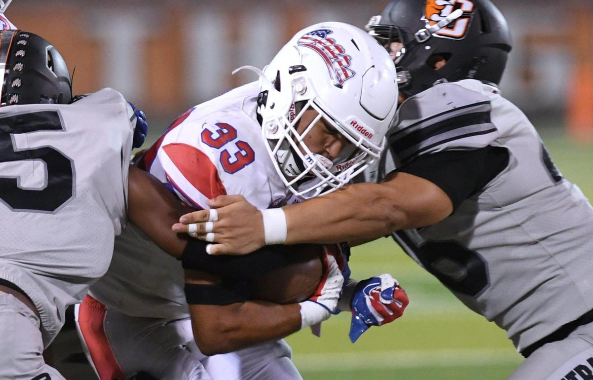 Buchanan’s Michael Runnels, center, is smashed by Central’s Jamari Carter, left, and Aidan Chavez, right, on a carry Friday, Oct. 7, 2022 in Fresno. Buchanan won.