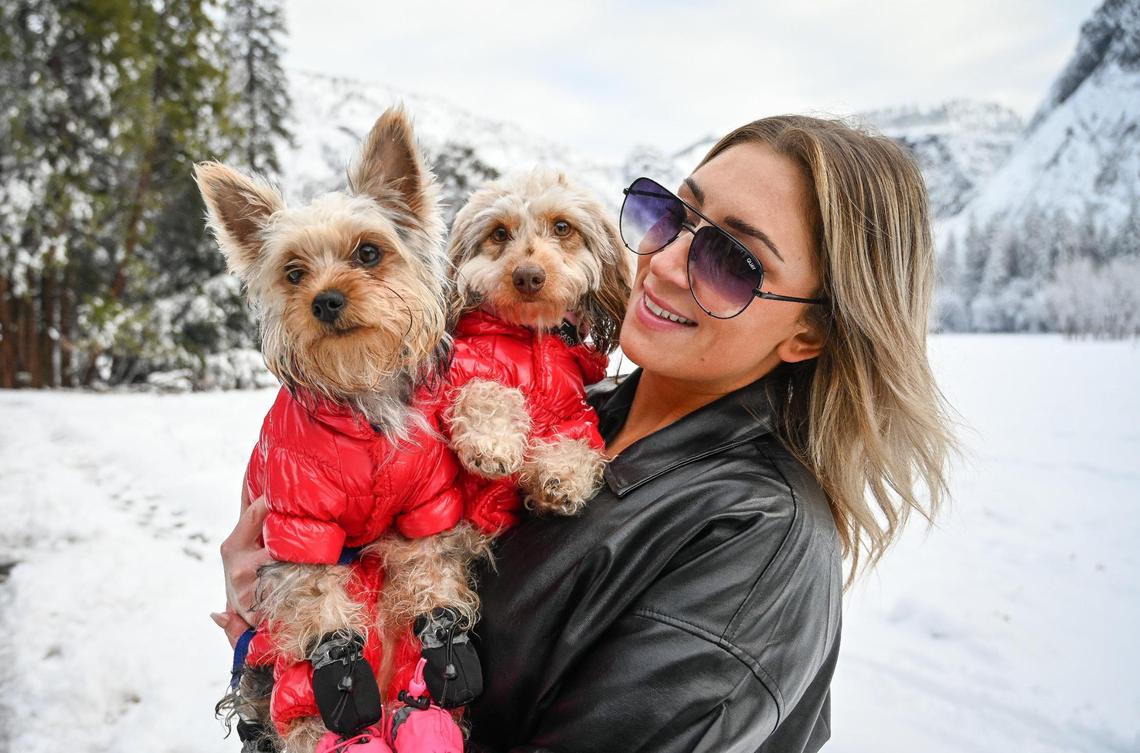 Leah Garcia, of Merced, holds her bundled-up dogs Louie, left, and Bowie, after taking photos with a snowy backdrop in Yosemite Valley on Wednesday, Dec. 15, 2021, following a snowstorm the day before.