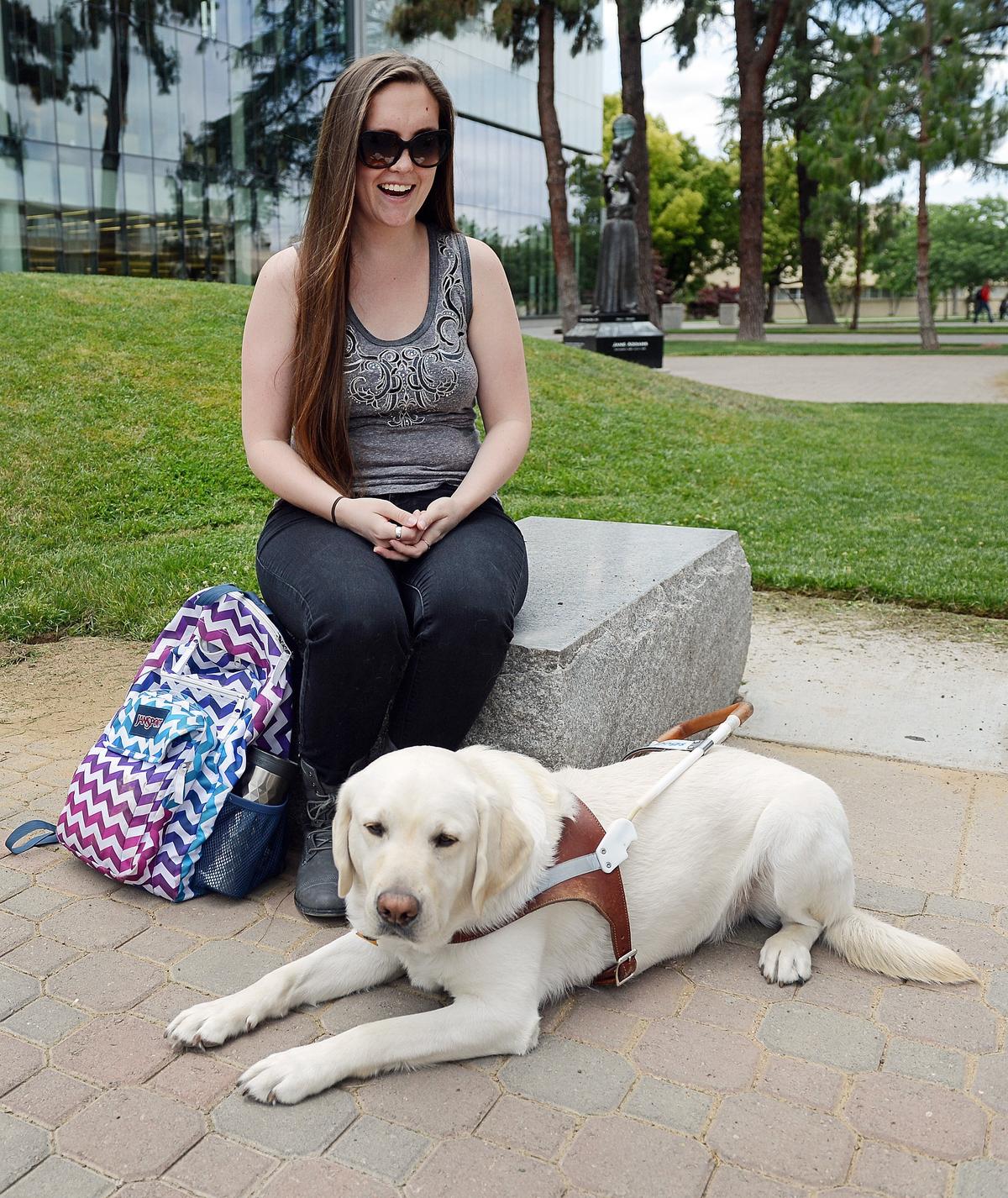 Shaela Warkentin, who lost her sight in a car accident in 2011, sits with her guide dog Lennox in the Fresno State Peace Garden on Wednesday, May 16, 2018. Shaela is graduating Friday from Fresno State.