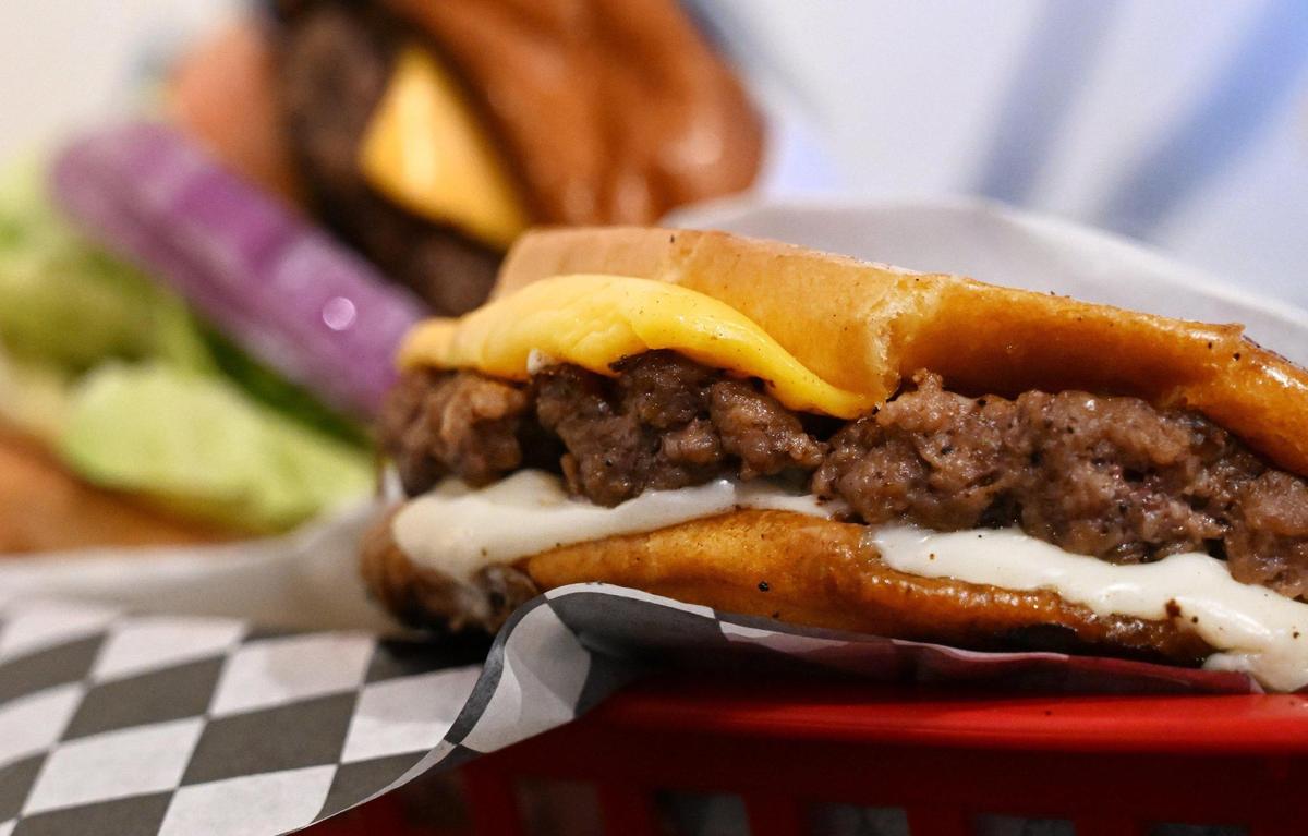 A Grumpy-style “smushed” burger is seen to the right, one of the many featured burgers from Take 3 x Grumpy Burger Lady’s on Fulton Street in downtown Fresno, California.