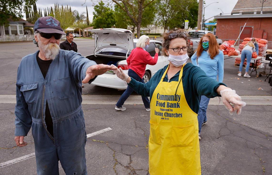 Victoria Salwasser, right, directs Curtis Smith, left, as volunteers distribute food to families in cars at a food bank giveaway held at Easton Presbyterian Church Monday, April 6, 2020 in Easton.