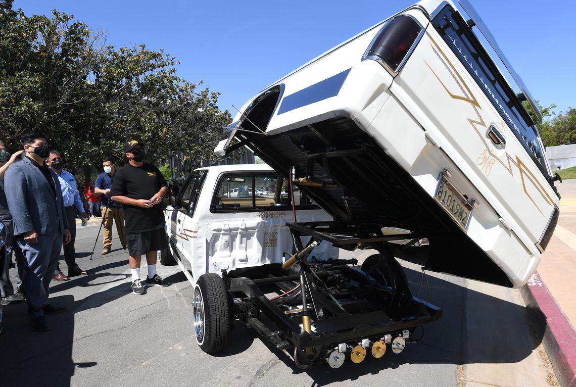Juan Vargas, in black, shows Fresno City Councilmember Luis Chavez, left, the hydraulics in action on his 1990 Mazda, nicknamed the “Ghost,” during a gathering of lowrider car enthusiasts at City Hall, Monday April 12, 2021, to kick off the Cruisin’ For Peace event to support Fresno’s street vendors, to be held in late April or early May. The route of the cruisers will take them down Kings Canyon Road and Fulton Street and end at Chukchansi Park.