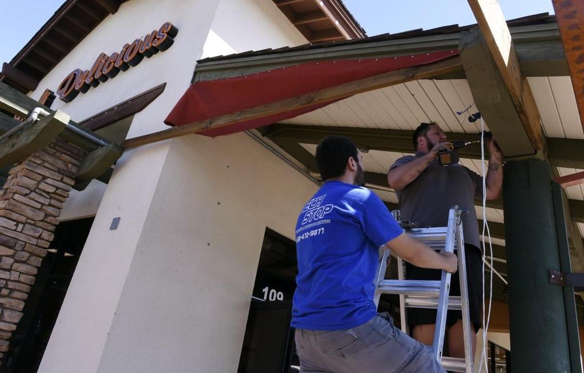 Workers install an outdoor speaker system at the new location for Deli Delicious, which is moving to a back corner of Fig Garden Village, shown on Wednesday, Sept. 20, 2017 in Fresno. Deli Delicious is just one of several new developments in the shopping area.