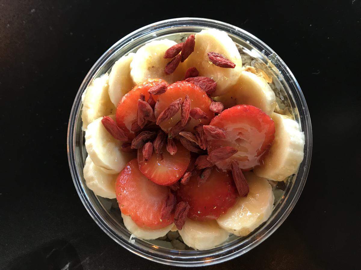 A bowl with a pineapple-coconut sherbet as its base, topped with bananas, strawberries and goji berries.
