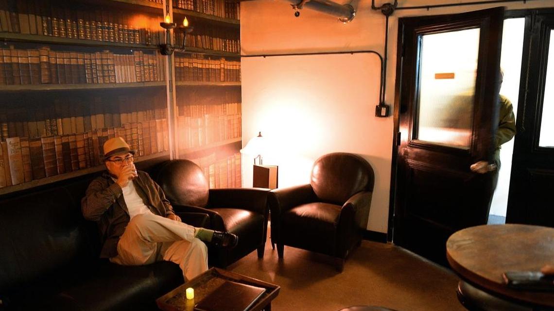 A patron relaxes with a drink as others enter The Library, a speakeasy bar upstairs at Detention Billiards in the Tower District, on Thursday, Nov. 30, 2017. Like other bars in Fresno County, The Library is now closed due to the COVID-19 pandemic.