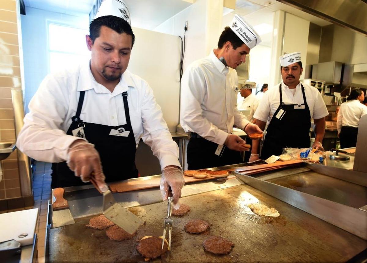 At the Fresno Steak ‘n Shake, which opened last March, cook Daniel Aguilar, left, and other employees practice for opening day.