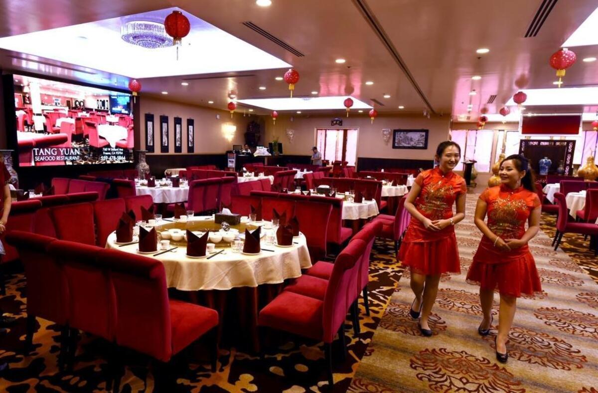 Tang Yuan restaurant hostesses Jaslynn Ekvixysack, left, and Menghua Yuan, right, walk through the large dinning room.