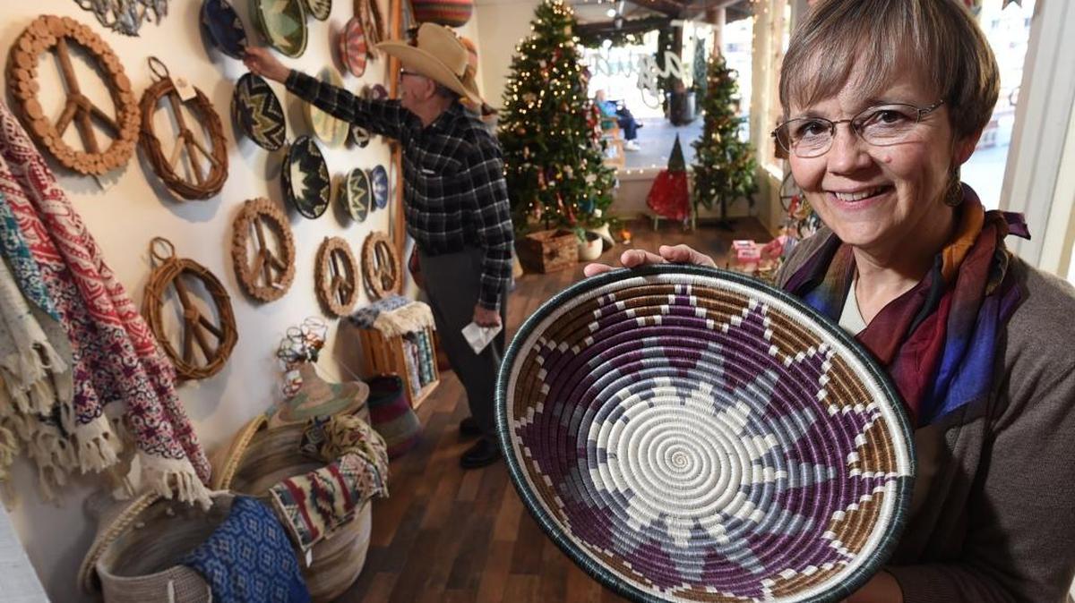 Kathy Heinrichs Wiest, a manager and board member of the Tagua Fair Trade nonprofit store in Fig Garden Village, shows a basket woven by craftswomen in Rwanda, made from dyed sisal fibers and sweet grass.