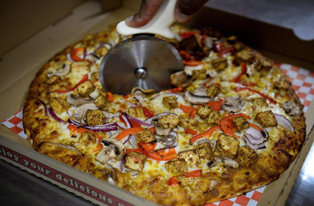 Malhi Singh of The Curry Pizza Company slices up a butter paneer pizza at the restaurant in Fresno on Thursday, June 7, 2018.