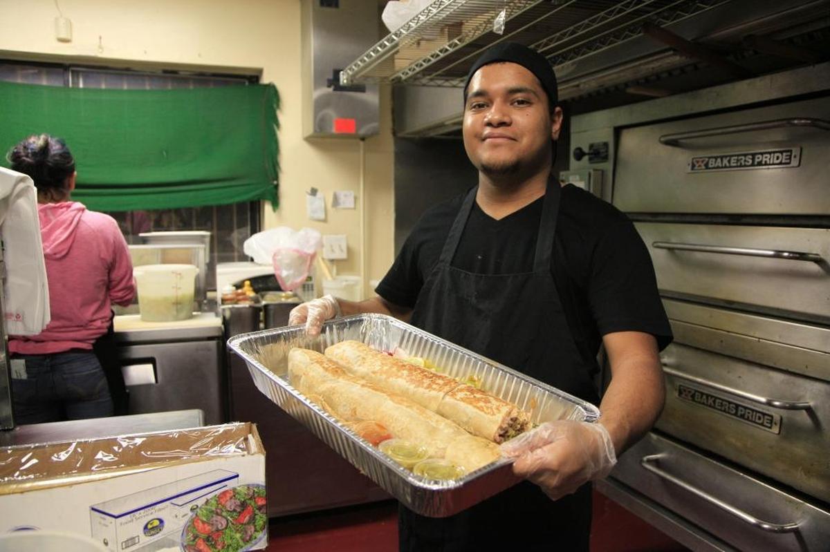 Edwin Espinoza of Taqueria Yarelis of Fresno holds an Anaconda burrito, which is about 3 feet long when whole. A video of the burrito went viral in 2016.