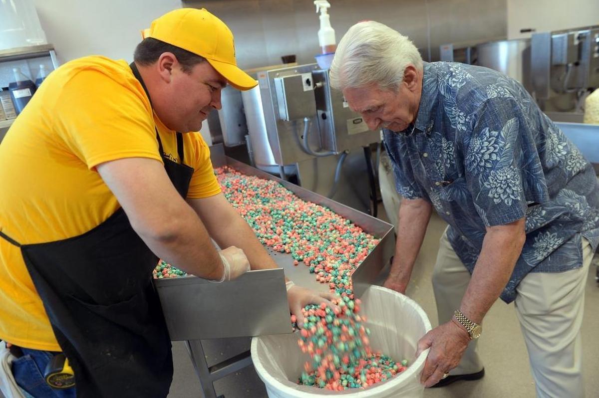 Daniel Campbell, 32, left, and his grandfather Fred Campbell, 78, mix freshly popped strawberry and blue raspberry-flavored popcorn to make their cotton candy-flavored popcorn at Grandpa’s Popcorn & Sweets on April 12 in Fresno.
