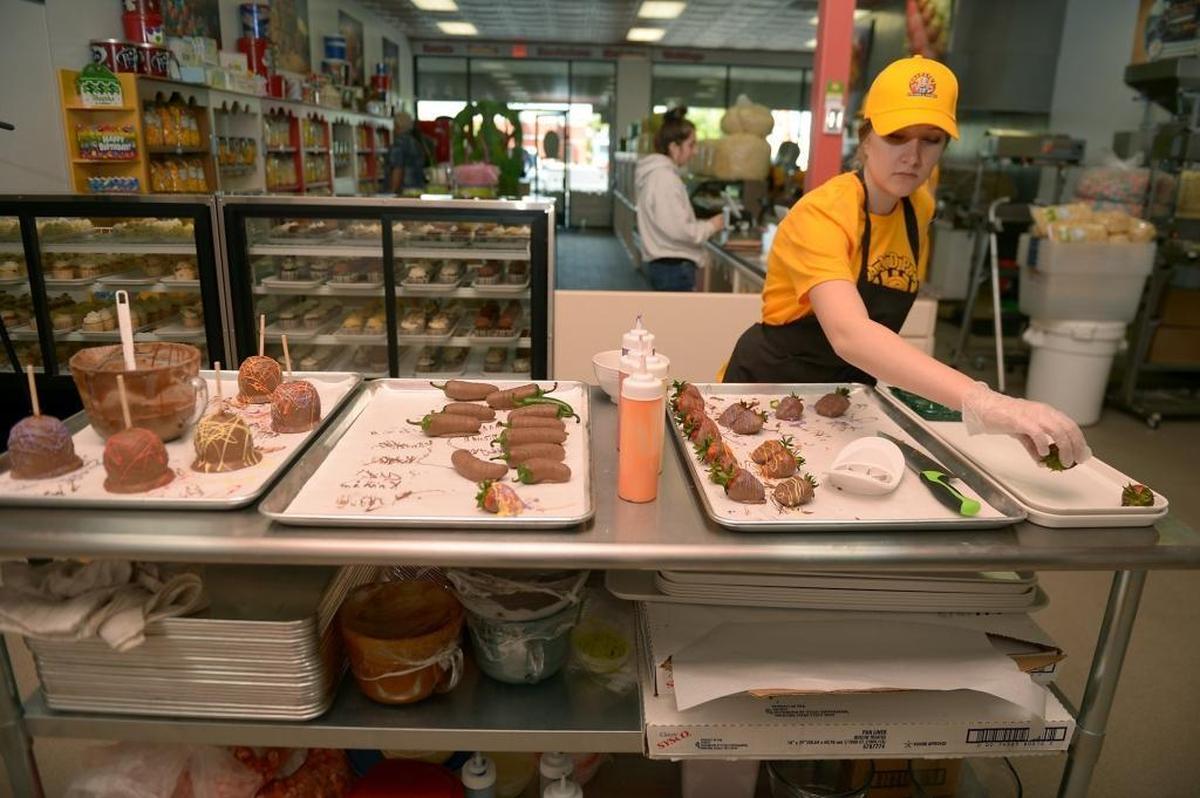 Jennifer Reddehase makes chocolate-dipped strawberries, jalapeños and apples in the kitchen at Grandpa’s Popcorn & Sweets on April 12 in Fresno.
