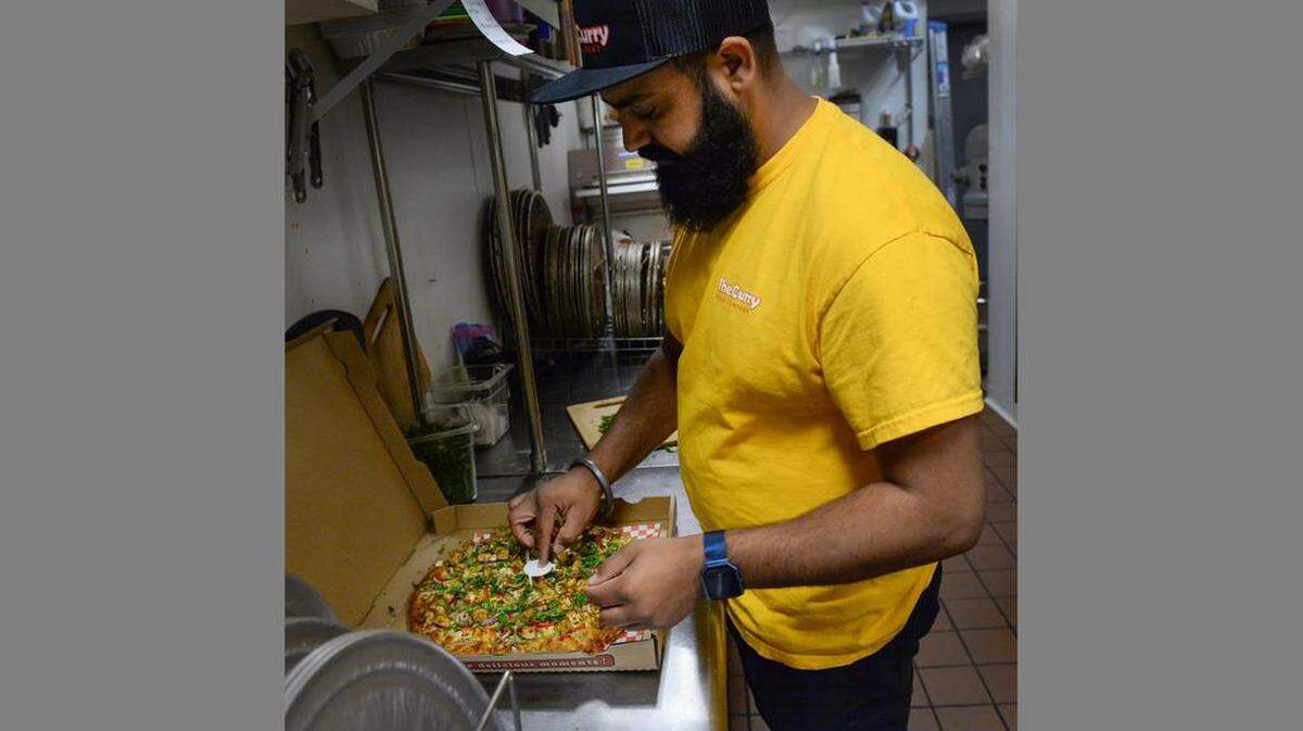 Malhi Singh of The Curry Pizza Company boxes up a butter paneer pizza to go at the restaurant in Fresno in 2018.