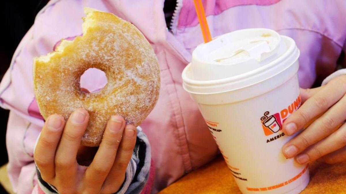 A customer eats a doughnut and coffee from Dunkin’ Donuts in an Associated Press file photo. The doughnut chain will open its first Valley location March 8 in Hanford.