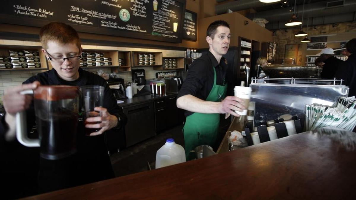 Baristas Lindsey Pringle, left, and Josh Barrow, right, prepare iced and hot Starbucks drinks, at a Starbucks Corp. store in Seattle, Friday, April 27, 2012. The coffee giant is giving away free espresso beverages from 1 p.m. to 2 p.m Friday Dec. 23 through Monday, Jan. 2, but customers must refer to Starbucks’ website to figure out which locations are offering the drinks.