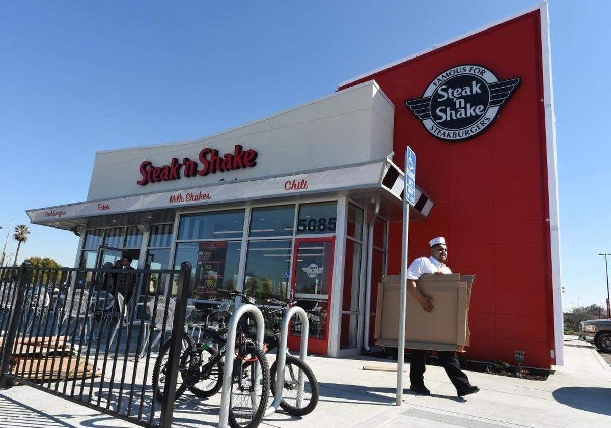 Steak ‘n Shake employee Felix Rios carries out empty boxes during the restaurant’s set up Wednesday morning.