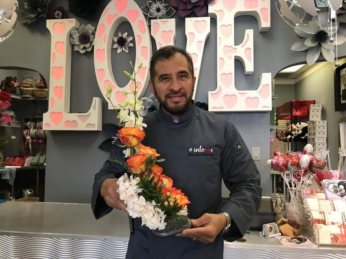Jorge Flores poses with a popular flower arrangement that displays roses in a stiletto at the #inlove Flower Shop and Home Decor on West Shaw Avenue.