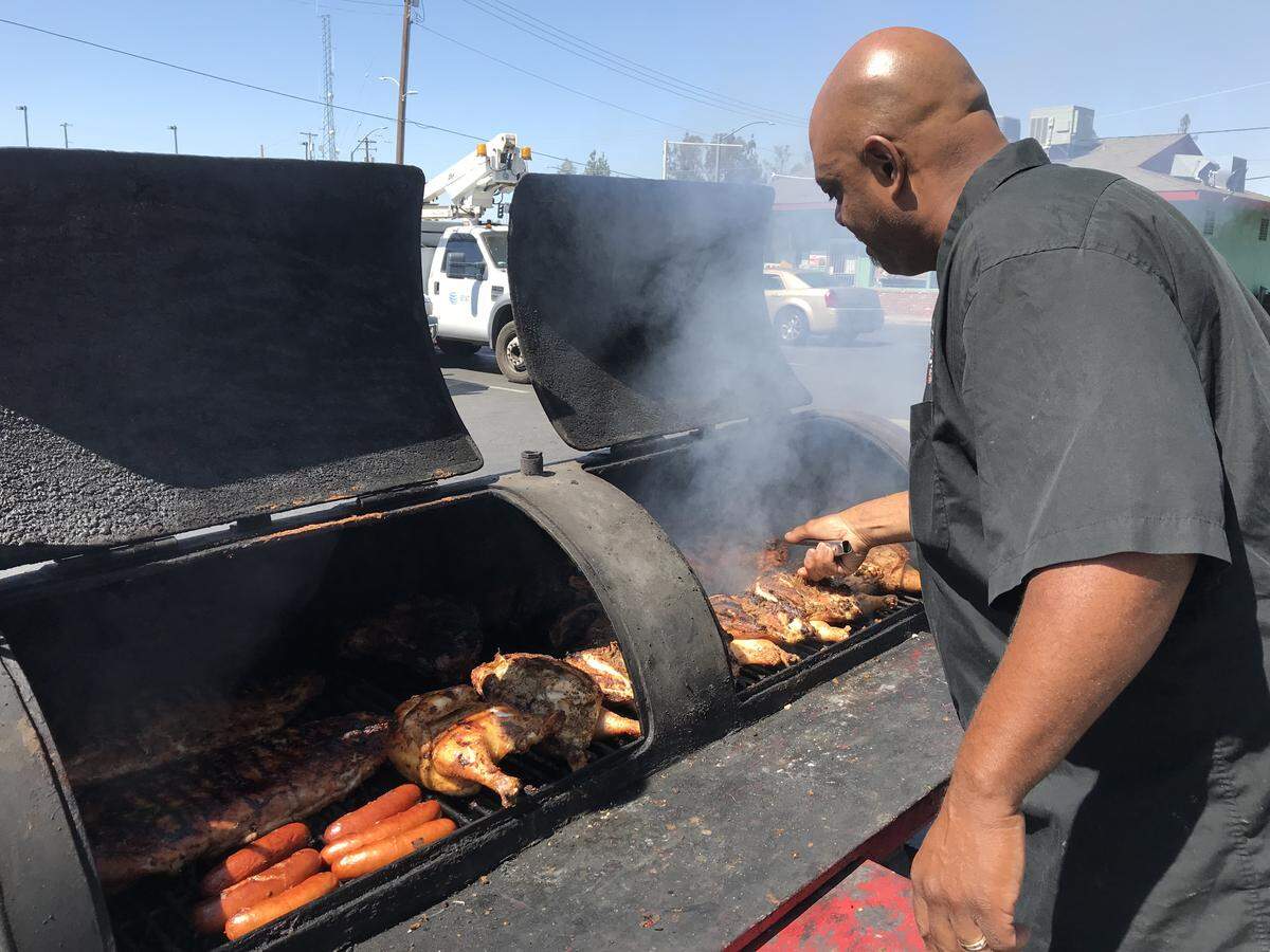 Phillip Young of Phill’s Corner Grill tends the meat in the smoker outside his restaurant at the Peacock Market at Tollhouse Road and Sunnyside Avenue in Clovis.