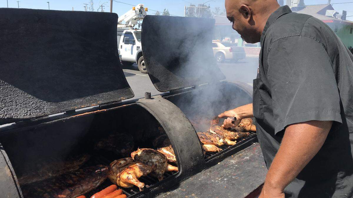 Phillip Young of Phill’s Corner Grill tends the meat in the smoker outside his restaurant at the Peacock Market at Tollhouse Road and Sunnyside Avenue in Clovis.