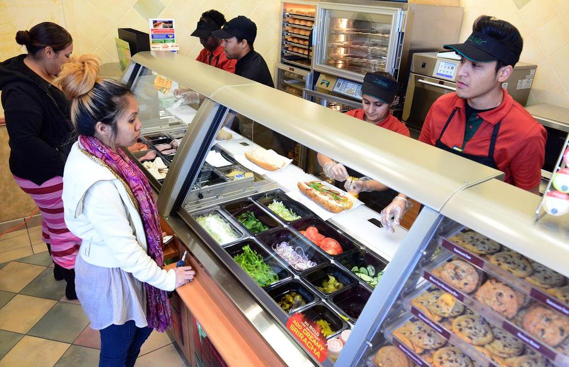 Subway employees serve customers in a Subway sandwich shop at 855 M. Street in 2014 in this file photo. The shop is seeing fewer customers because IRS workers in the same building have been furloughed or are working without pay.