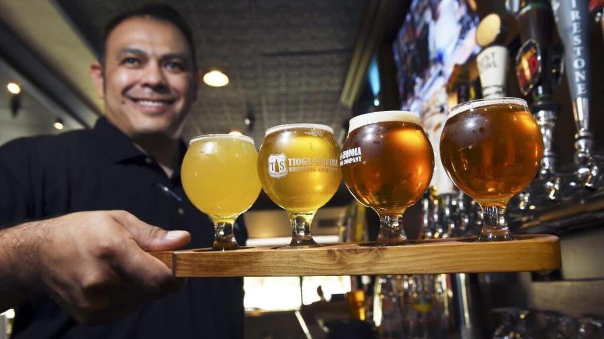 Bartender Eric Garcia presents a flight of beer at Taps & Tacos in Fresno. Taps & Tacos is just one of several places catering to customers with the explosion of beer on tap’s popularity.