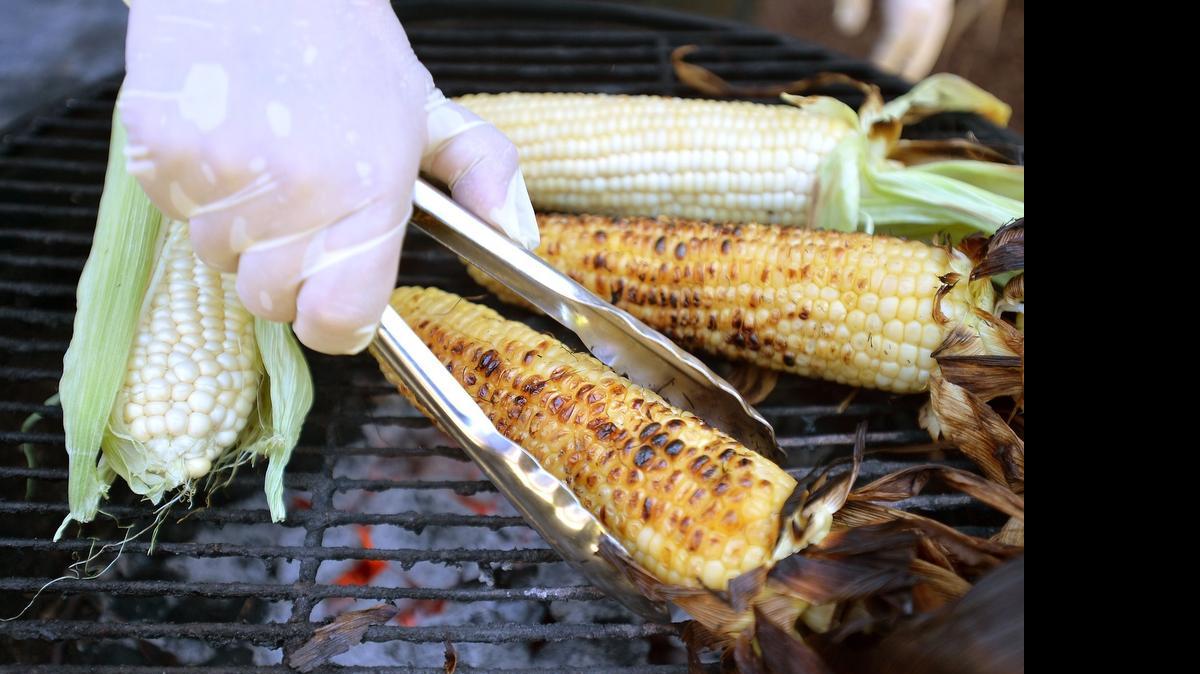 
Pete Ramirez, owner of Meltdown Bistro, a local food truck, roasts corn on the cob on a charcoal grill.
