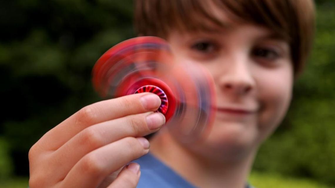 Ford Hedgepath, 12, checks out his fidget spinner, a hot toy. The two or three-pronged gadgets spin endlessly with the help of bearings and weights.