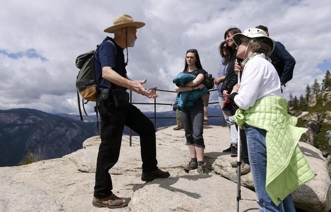 George Whitmore, left, then 85, one of three men on the first team to climb El Capitan in Yosemite Valley, answers questions from visitors who learn of his 1958 feat during a hike to Taft Point on May 26, 2016 in Yosemite National Park.