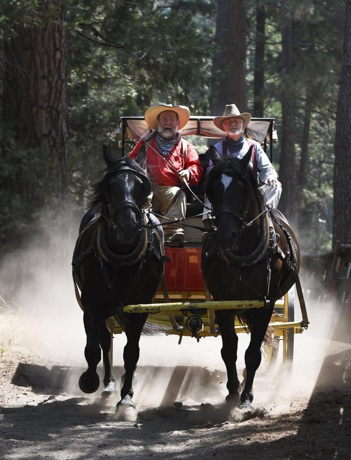 Burrel “Buckshot” Rambo Maier, left, with Ron Townsend riding as his swamper, right, drives the stagecoach with tourists riding in the coach through a dusty portion of his route in Wawona, Yosemite National Park, Thursday, Aug. 3, 2017.