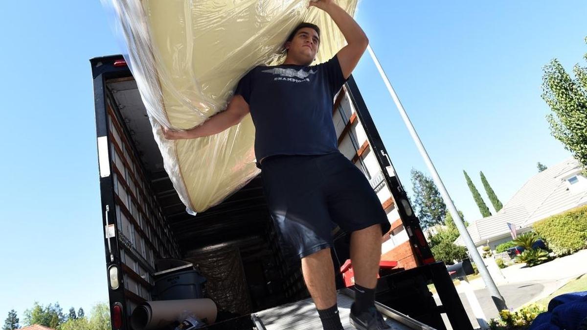 Meathead Movers worker Theo Stratigos, a former Bullard High School football and rugby player, moves a bed into a home Sept. 28, 2017.