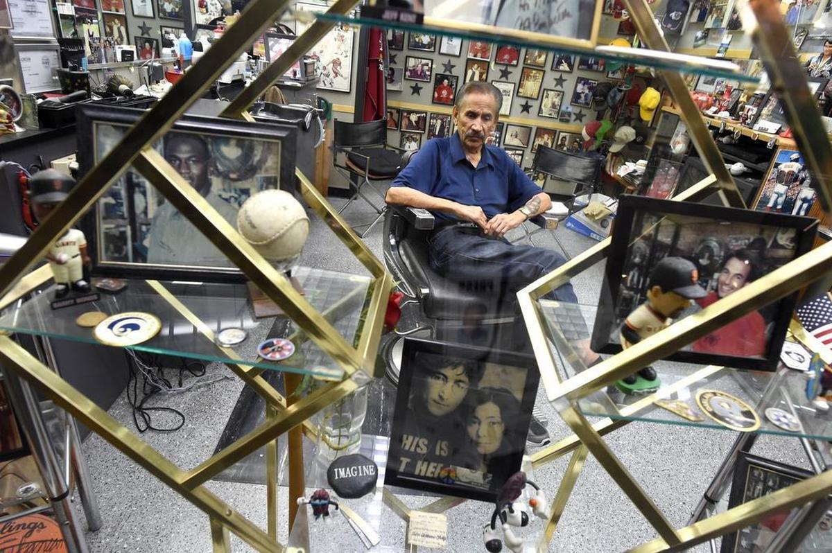 Barber Nick Palomares sits in his chair in his shop at Fresno Yosemite International Airport in 2017, surrounded by photos, autographs and mementos of famous people he’s encountered over more than half a century of cutting hair.