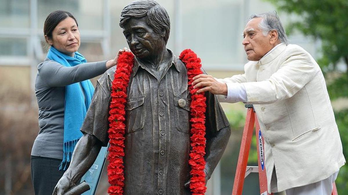Julie Chavez Rodriguez, granddaughter of civil rights leader Cesar Chavez, and Fresno State emeritus faculty member Dr. Sudarshan Kapoor, place a garland around the statue of Cesar Chavez in 2018. The statue was placed in storage after it was revealed that Chavez sexually abused girls and young women.