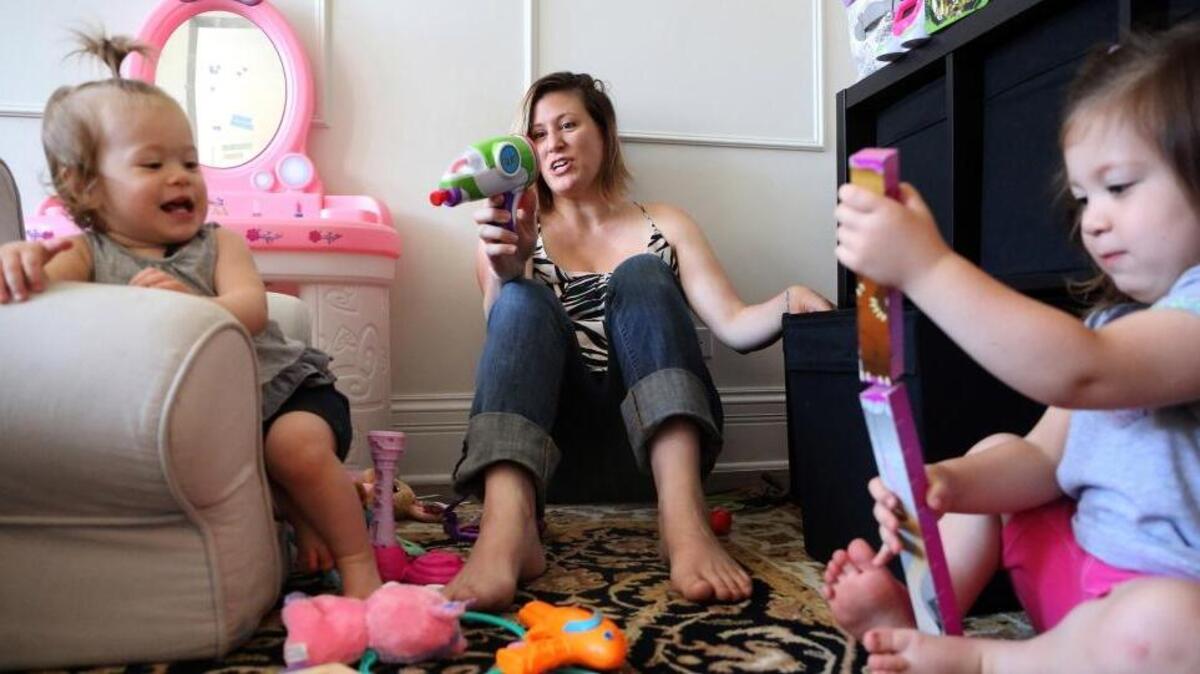 Lori Sapio plays with daughters Oona, 1, left, and Viola, 3, at their Chicago home. Sapio, who is a professional photographer and a mother of two, planned on staying home with her kids but went back to work days later.