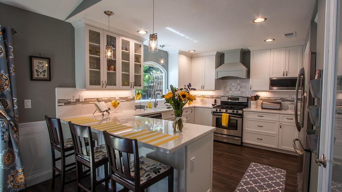 White cabinets and gray walls are very much “on trend” for 2016 remodeled kitchens. Also featured in this design by Sacramento-based Kitchen Mart are dark wood plank floors, stainless steel appliances, marble-look quartz countertops and an open, airy floor plan.