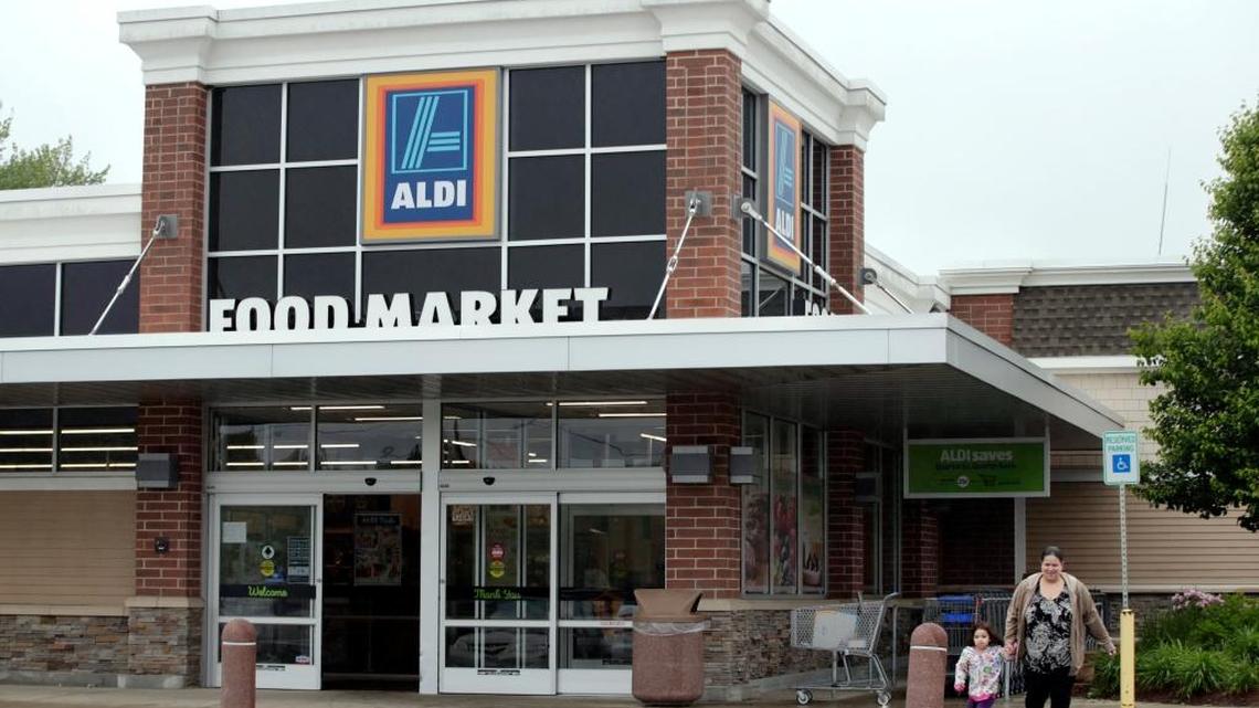 In this June 5, 2017 photo, a woman and child walk from ALDI food market, in Salem, N.H. Low-cost grocery chain ALDI says it plans to add more stores in the U.S. over the next five years, meaning more competition for traditional grocers, Walmart and organics-focused chains like Whole Foods.