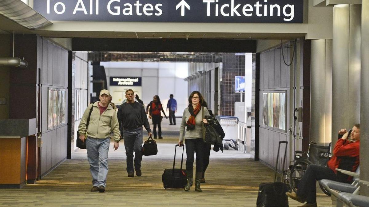 Travelers walk to the rental car/baggage pickup area in the terminal at Fresno Yosemite International Airport.