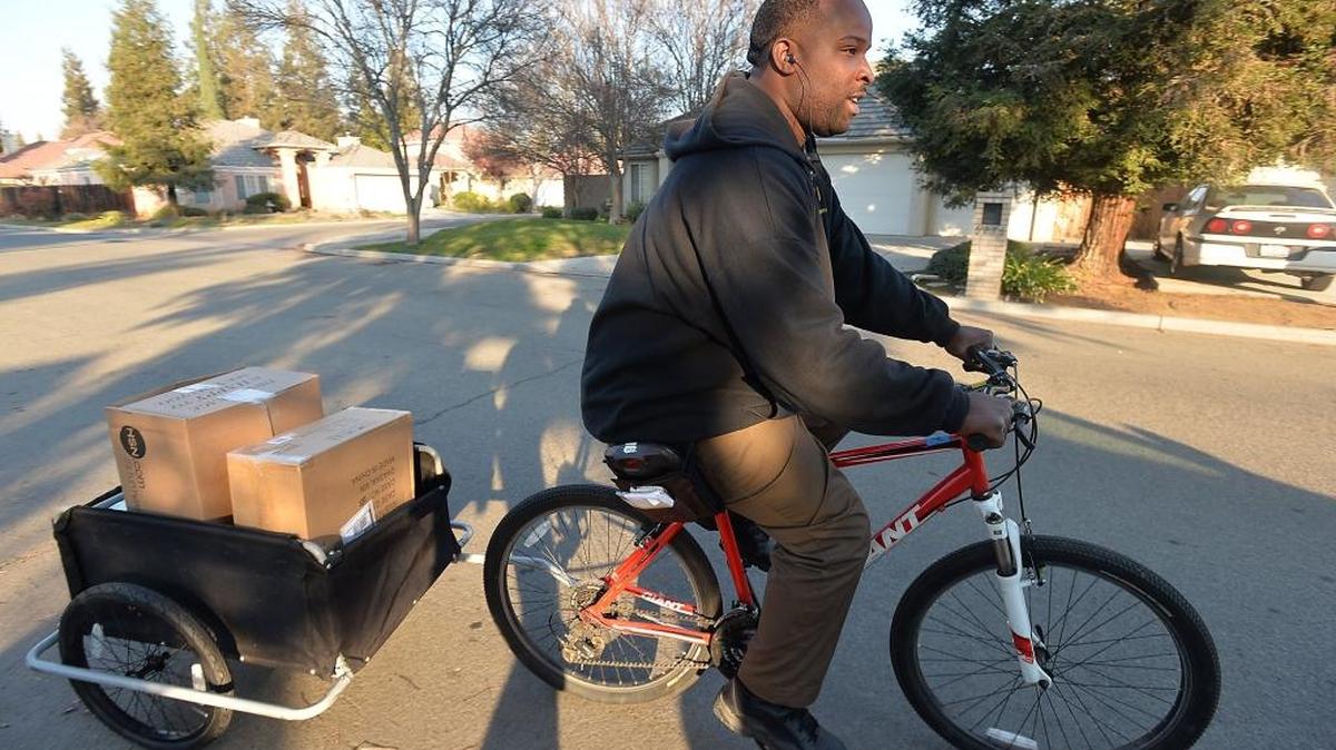 United Parcel Service worker Derrick Ricks transports packages for delivery on a bike on Thursday, Dec. 17, 2015, in a northwest Fresno neighborhood.