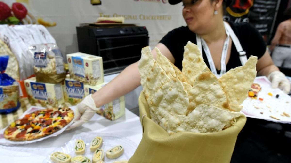 On a table with their various products, Sarah Dunn of Valley Lahvosh Baking Company puts out a pizza on the company’s cracker bread at the Fresno Food Expo in July 28, 2016.