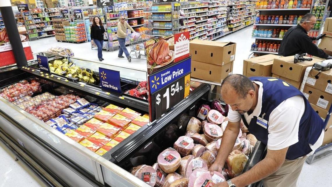 Andrew Ramiro, a Walmart meat department associate, stocks hams in the newly expanded section of the Walmart at 7065 N. Ingram Ave., Thursday afternoon. The expansion will be complete later this month.