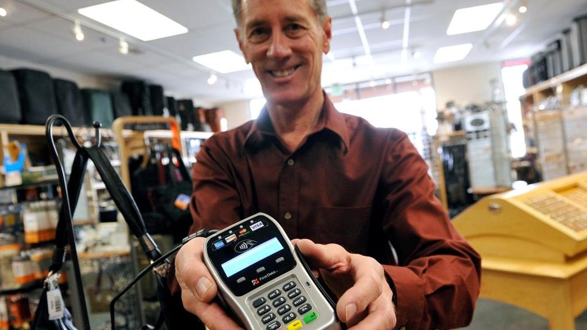 Craig Pokorny, owner of Aporjon Leather & Luggage in Fresno’s Fig Garden Village, shows the new chip card reader he has been using to offer increased security for customer transactions since October 2014.