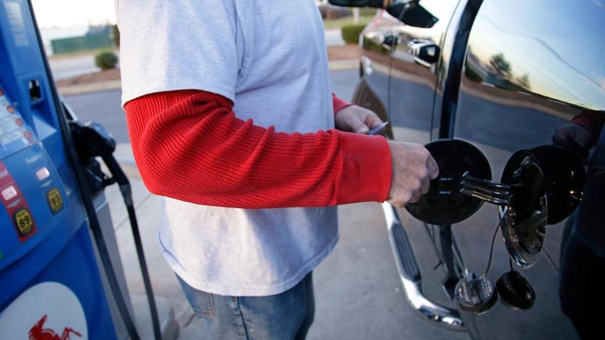 A customers opens the fuel door on his pickup truck before pumping at a gas station Monday, Dec. 7, 2015, in Pembroke, Mass. With OPEC unwilling to cut back on production, low oil prices seem almost guaranteed for at least the next few months. That’s good news for U.S. motorists and industries but bad news for states and countries that have seen their budgets busted as fuel tax collections have declined.