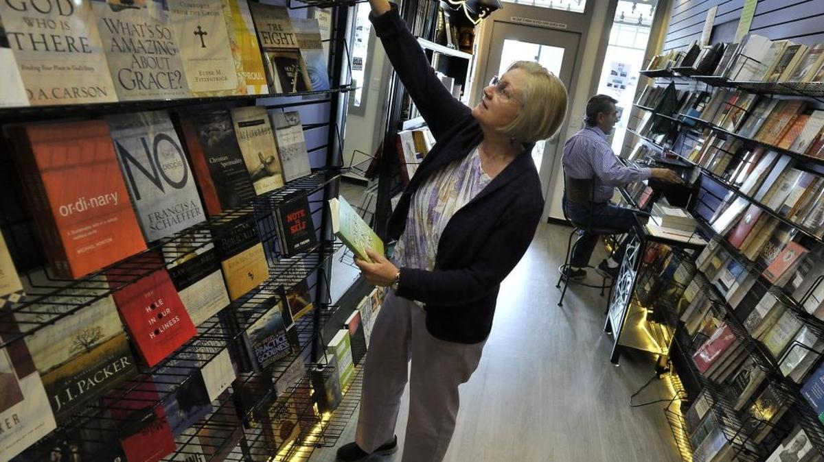 Linda Flores arranges books as husband, Ed Flores, does computer inventory work in their Clovis Book Nook.