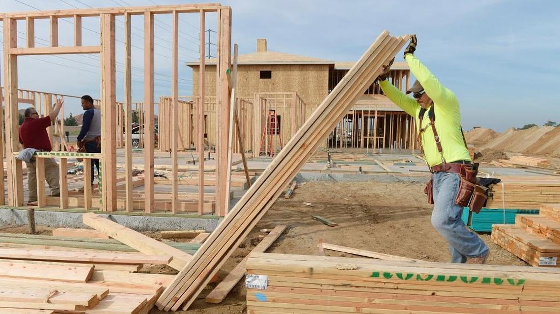 A worker tilts up a stack of lumber during construction on a home in a northeast Fresno development in this 2016 file photo.  Employment in construction rose to 19,500 in September 2018, a gain of about 1,500 from a year earlier.