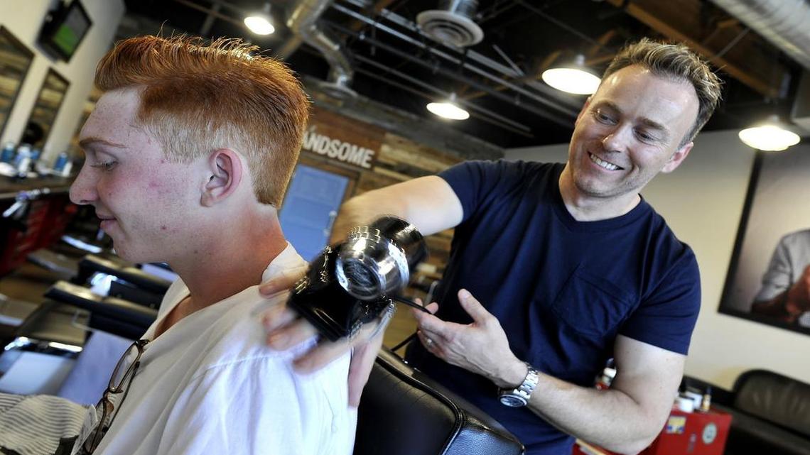 
Tye Featherstone applies an old-fashioned hand massager to the shoulders of Justin James after his haircut at Featherstone’s Great American Barbershop.
