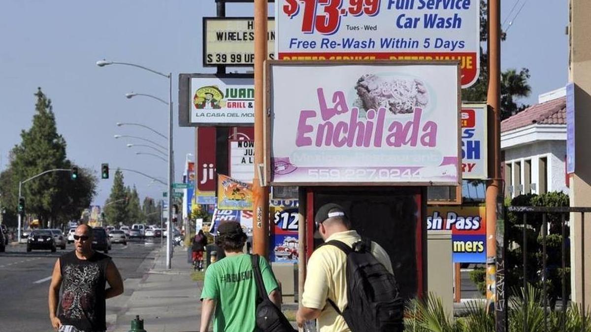Pedestrians walk along Blackstone Avenue just north of East Dakota Avenue in Fresno.