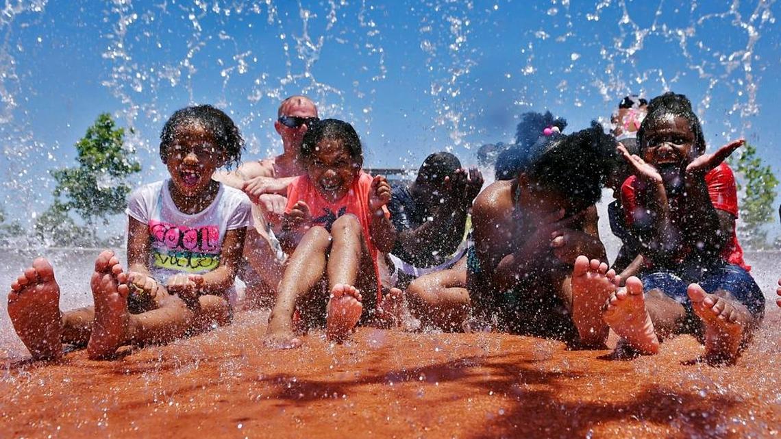 A group of girls gets drenched as a large bucket of water showers them at Fresno’s Inspiration Park on June 18, 2017.