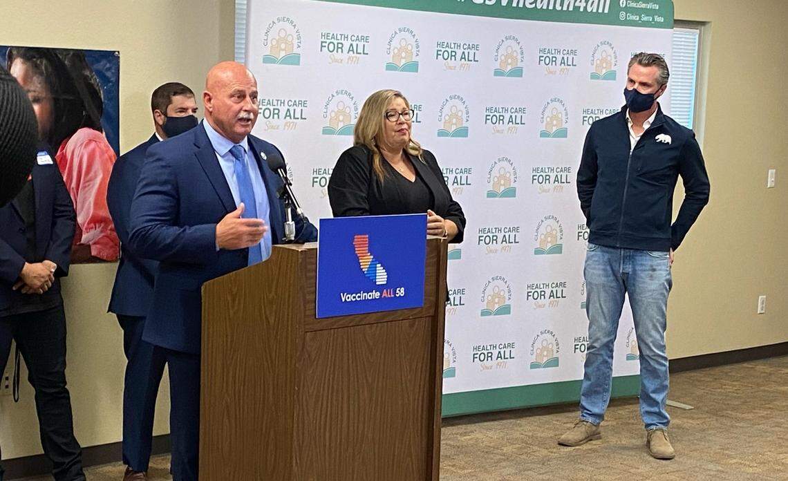 Gov. Gavin Newsom, far right, is shown while Fresno Mayor Jerry Dyer speaks on the reasons why he supports a law expanding health care for undocumented immigrants.