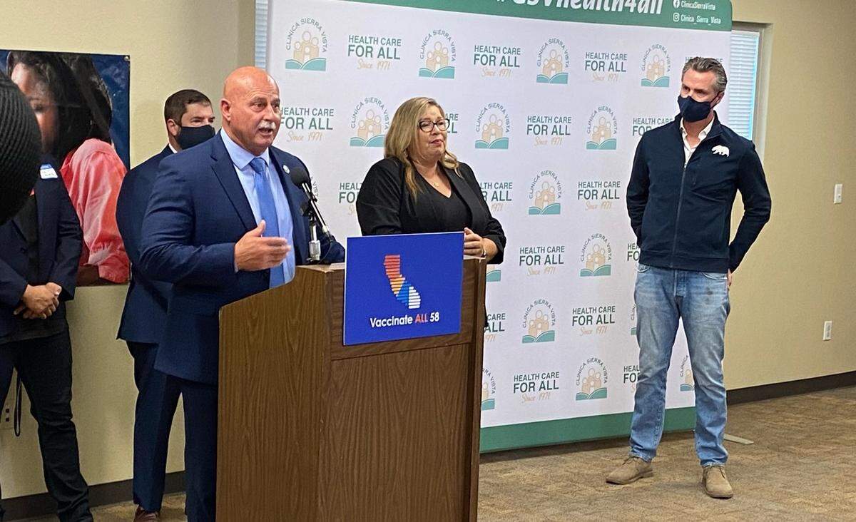 Gov. Gavin Newsom, far right, is shown while Fresno Mayor Jerry Dyer speaks on the reasons why he supports a law expanding health care for undocumented immigrants.