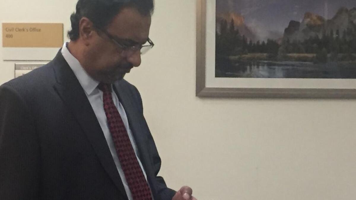 Dr. Pervaiz Chaudhry checks his cell phone Thursday during a break in his civil trial for medical malpractice in Fresno.